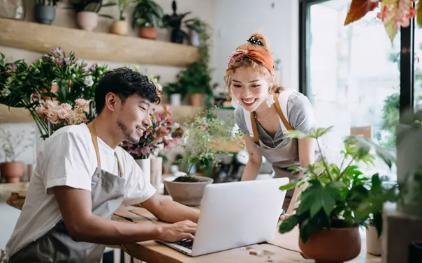 two business owners of flower shop looking at laptop