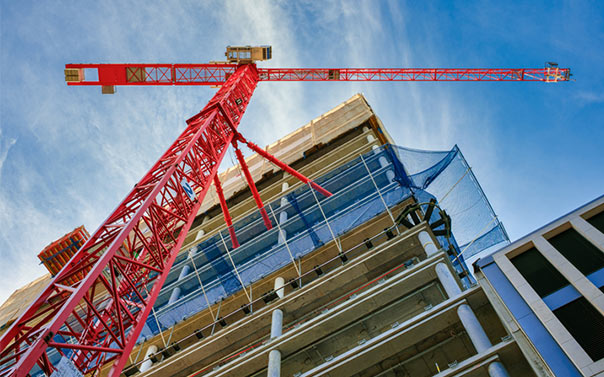 Looking up at the construction site of a high-rise building with red crane